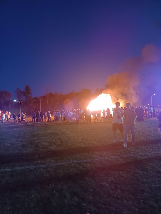 Wissahickon families and staff gather around, mesmerized by the flames of the fire